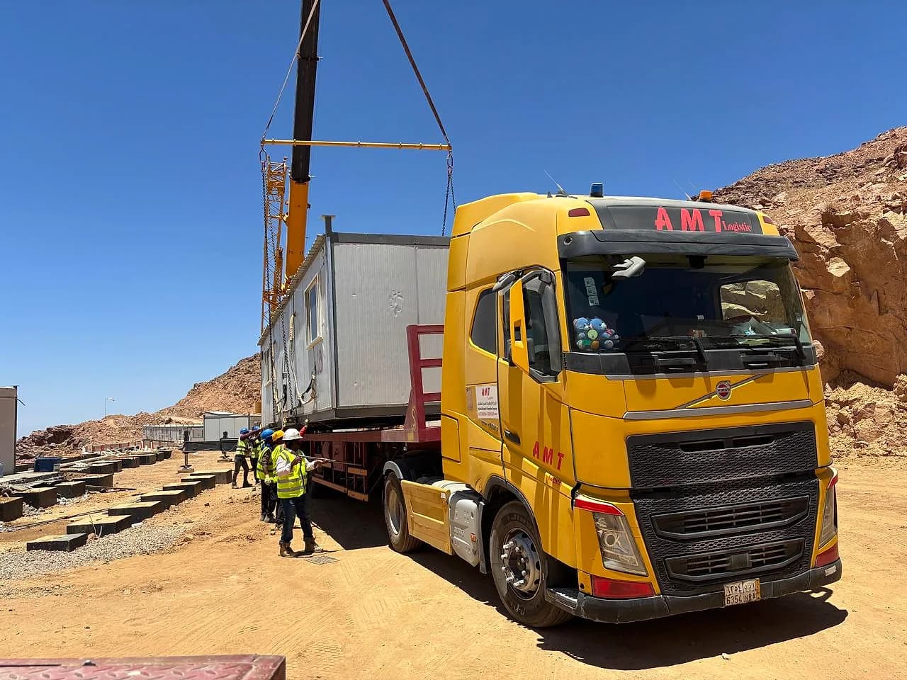 شاحنة AMT صفراء تنقل غرفة جاهزة مع تجهيز كرين